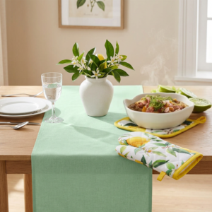 Sommerliche Tischdekoration mit mintgrünem Tischläufer, Zitronen-Ofenhandschuhen, Zitruszweigen und heller mediterraner Wohnatmosphäre.